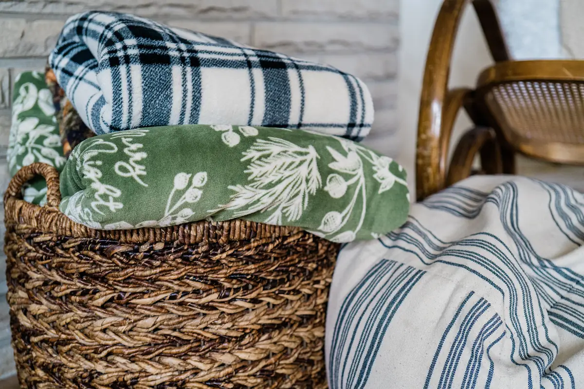 A wicker basket holding folded soft blankets and towels