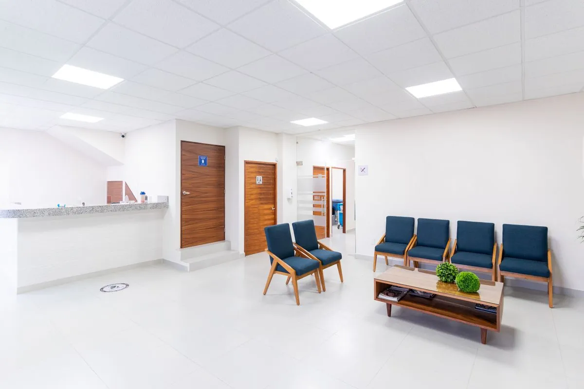 A clean, bright veterinary clinic waiting room with blue chairs and a reception counter