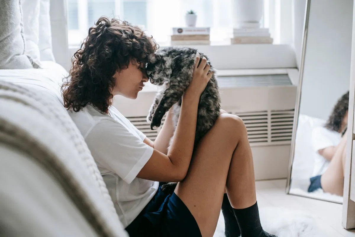 Owner sitting on the floor touching noses with her fluffy cat