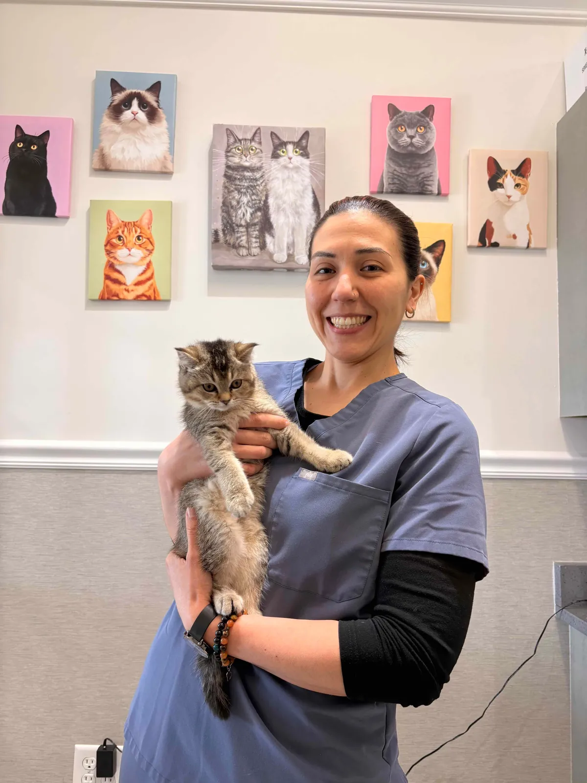 A smiling veterinarian holding a kitten during a vet clinic visit